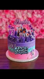 Purple and pink gradient K-Pop Demon Hunters themed birthday cake with character printouts and a custom name topper.