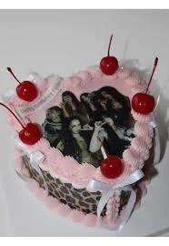 Heart-shaped pink vintage cake with leopard print sides, red cherries, and a K-pop group photo printout.