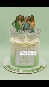 A green and white ombre cake with a photo printout of a group of women and heart-shaped name toppers.