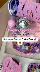 Pink Katseye themed bento cake with a disco ball topper, purple character printouts, and pink icing swirls.