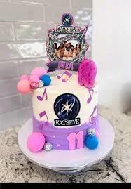 Katseye themed birthday cake with purple and white icing, musical notes, and character printouts for an 11th birthday.
