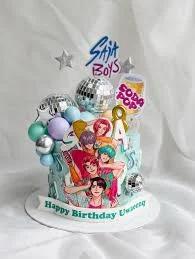 Light blue K-pop themed birthday cake with anime-style boy band printouts, disco balls, and colorful fondant spheres.