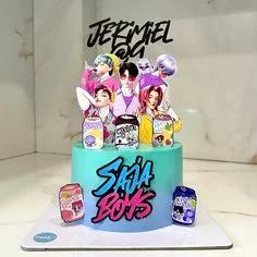 A vibrant blue and teal gradient cake featuring K-pop boy band printout toppers and a stylized 'SAJA BOYS' message.