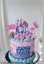 Pink and purple gradient cake with Kpop Demon Hunters character printouts and colorful lollipops.