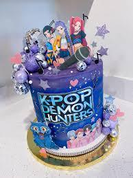 Tall purple Kpop Demon Hunters cake with character cutouts, disco balls, and musical note toppers