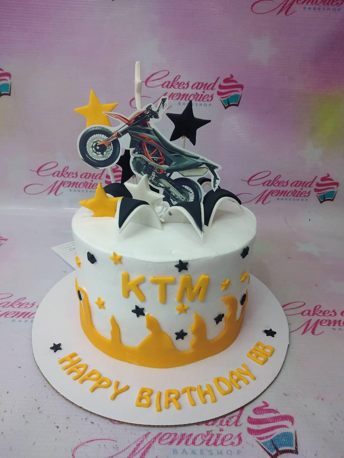 White 1-tier motorcycle themed birthday cake with yellow flames, black stars, and a KTM motorbike printout topper.