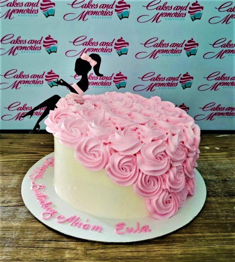 Elegant white cake with a cascade of pink icing rosettes and a black silhouette lady topper with a pink bow.