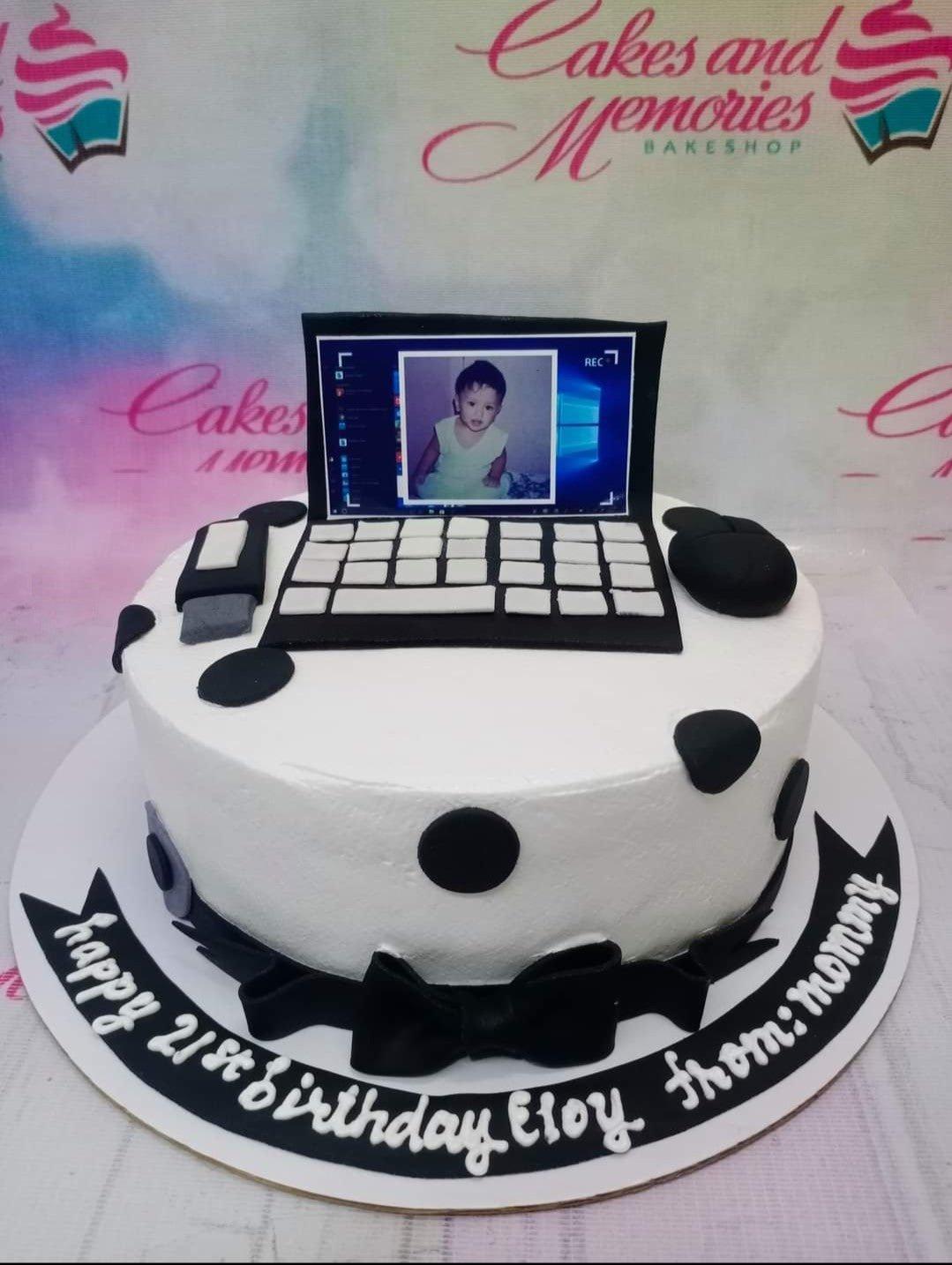 White fondant cake with black polka dots and a laptop topper featuring a photo of a child, decorated with a black bow and message banner.