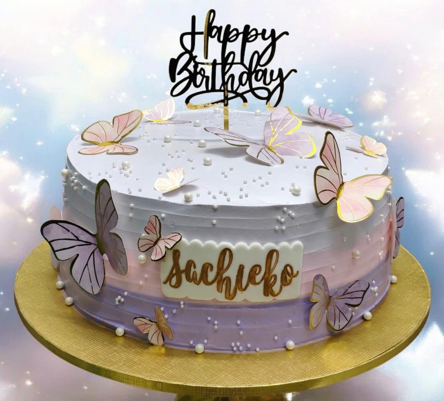 A single-tier lavender and white gradient cake decorated with pink and purple printout butterflies and white pearl sprinkles.