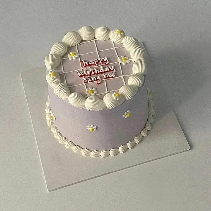 Lavender bento cake with white piped shell borders, white daisies, and a grid pattern on top with a Happy Birthday message.