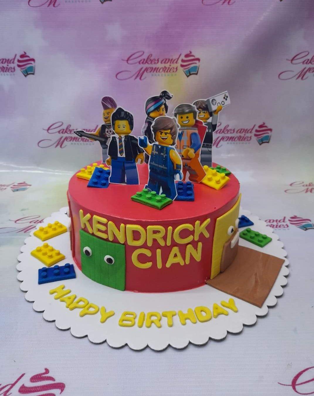 Red Lego Movie themed birthday cake with character printouts and colorful fondant building blocks.