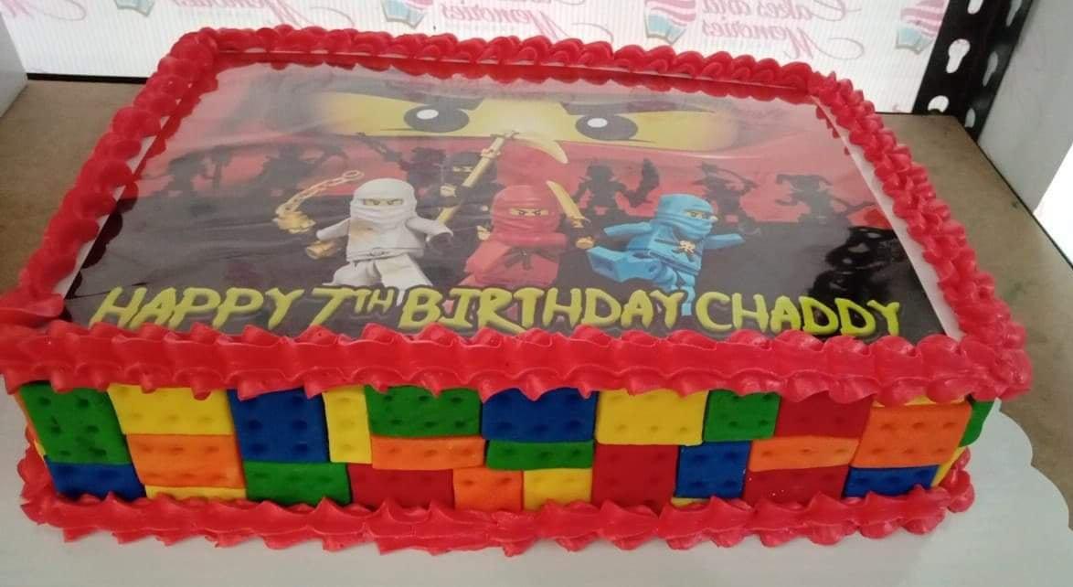 Lego Ninjago rectangle birthday cake with red icing borders and edible photo print of characters on top.