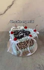 Heart-shaped leopard print cake with light green ruffled icing, red cherries, and white ribbons.