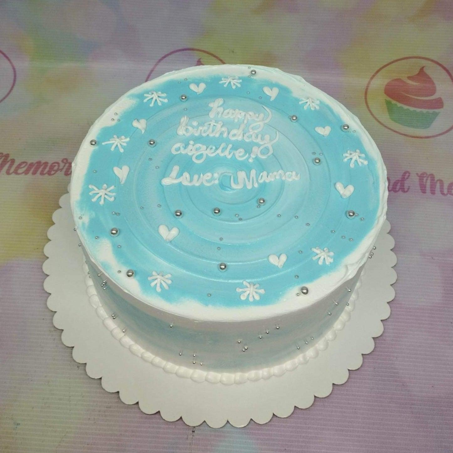 Light blue and white minimalist birthday cake with silver dragees and piped icing hearts and snowflakes.