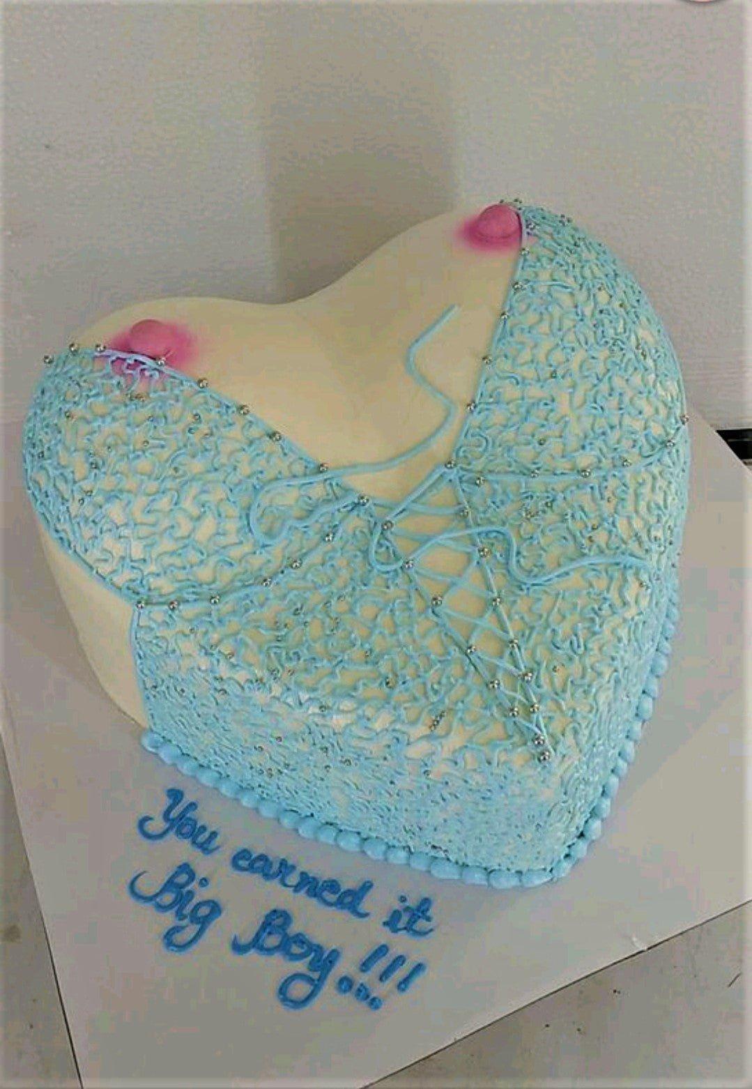 Heart-shaped novelty cake designed to look like a woman's torso wearing a blue lace lingerie set with pink accents and silver beads.