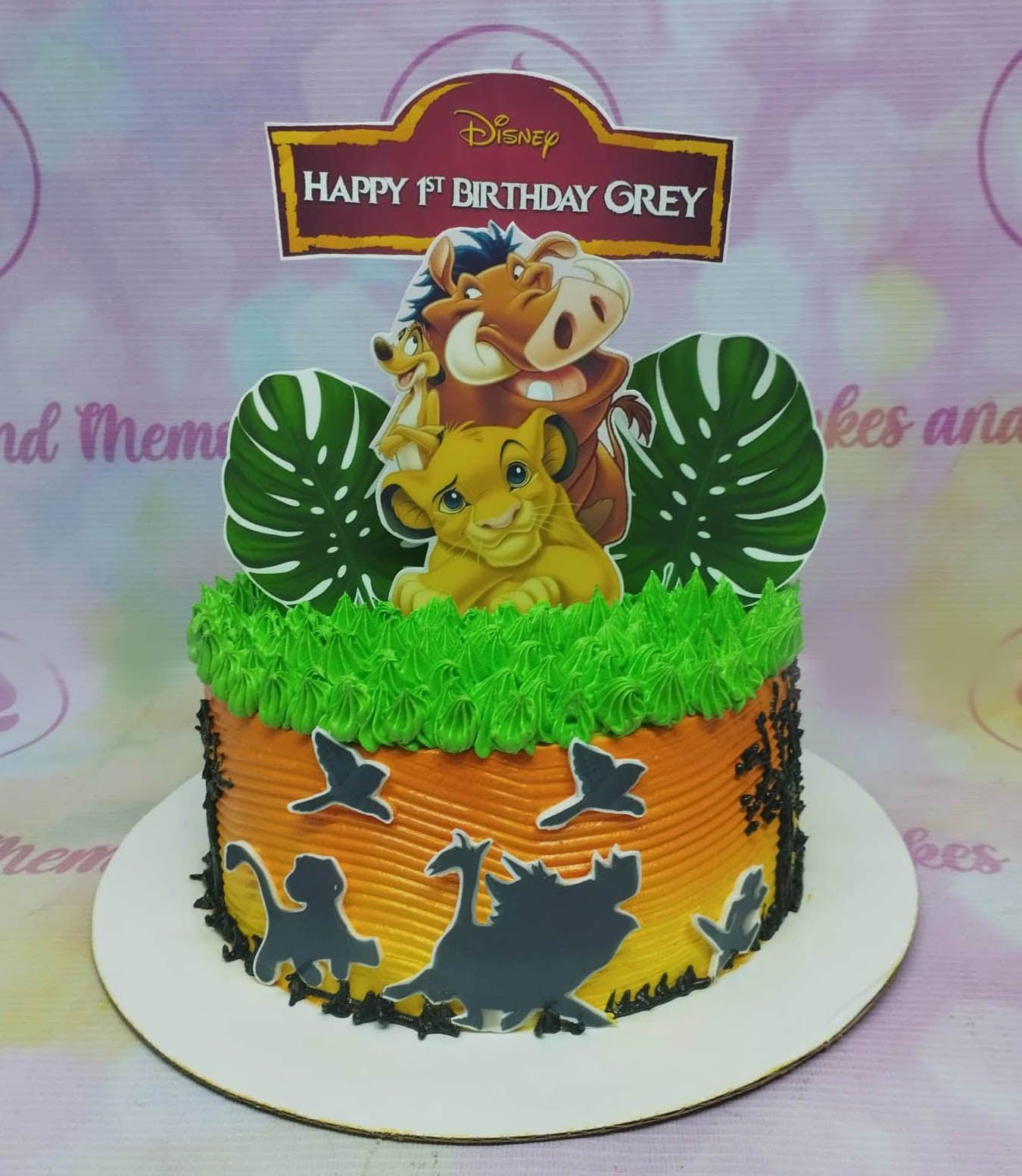 Lion King themed birthday cake with Simba, Pumbaa, and Timon toppers on orange and yellow gradient icing with green grass piping.