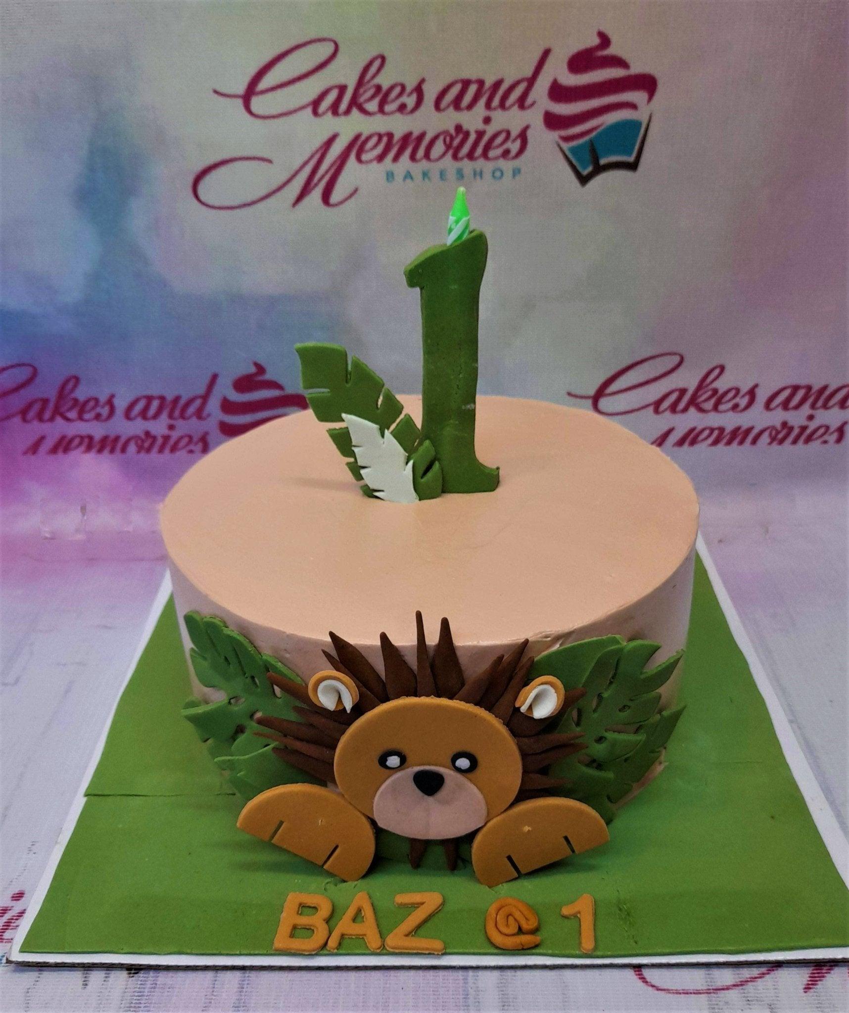 Peach lion safari birthday cake with green fondant leaves and a number one topper