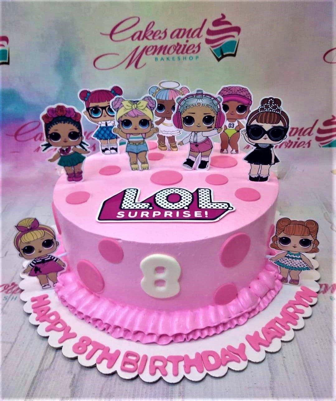 Pink LOL Surprise themed birthday cake with character printouts, pink polka dots, and a ruffled icing border.