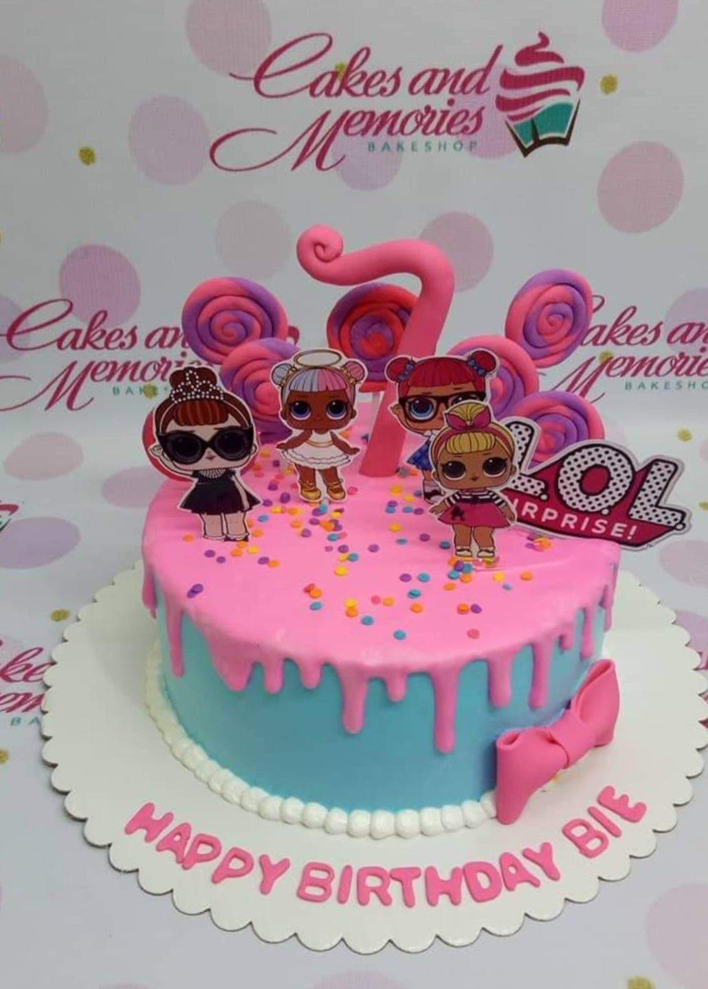 Pink and blue LOL Surprise themed birthday cake with pink drip, lollipops, and character toppers.