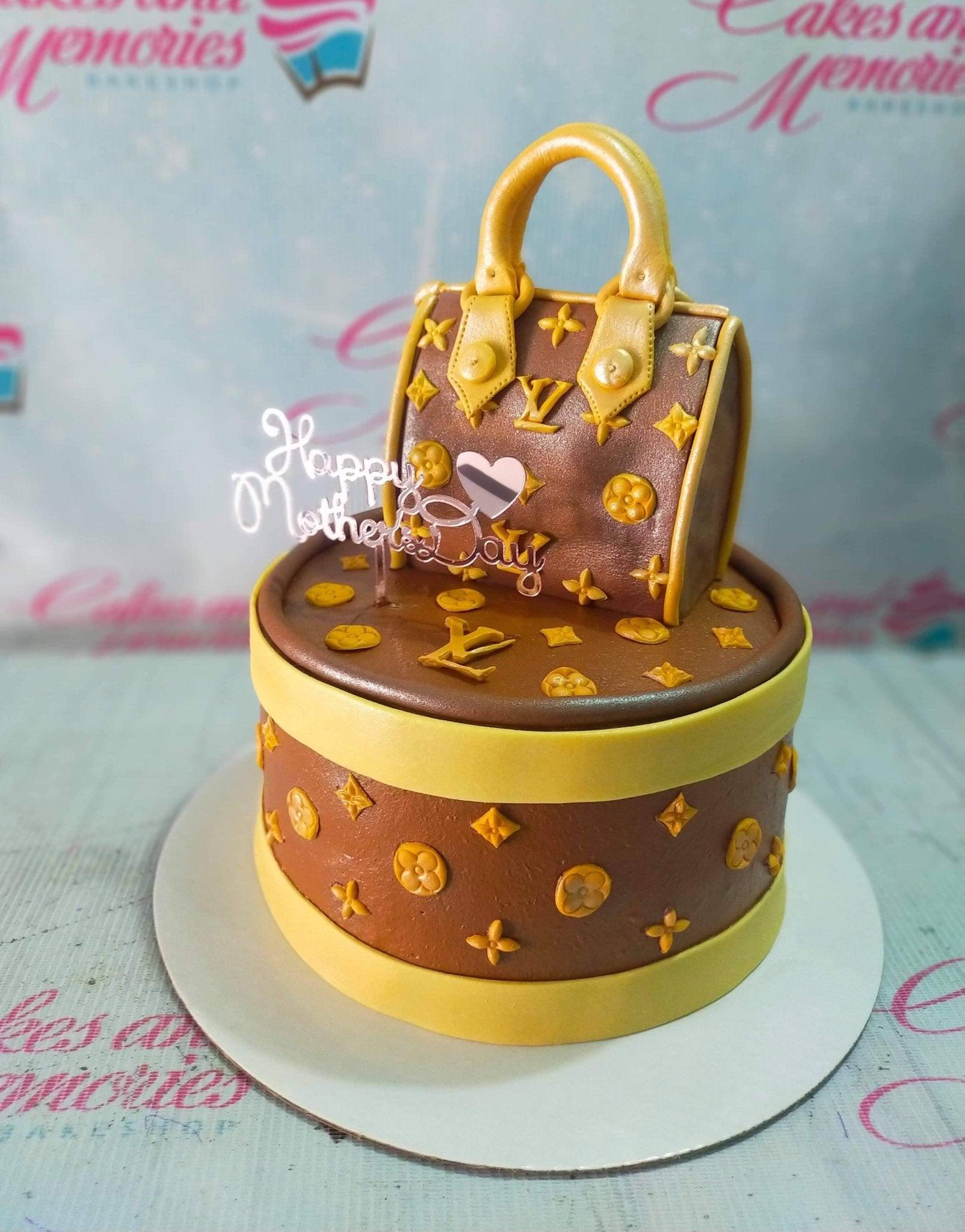 Brown Louis Vuitton designer handbag cake with gold monogram patterns and a pink acrylic Happy Mother's Day topper.