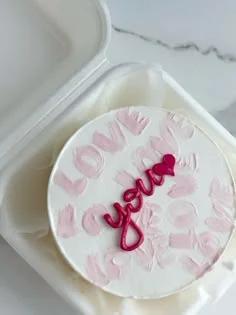 White bento cake with pink palette knife 'LOVE' patterns and a dark pink 'love you' piped icing message in the center.