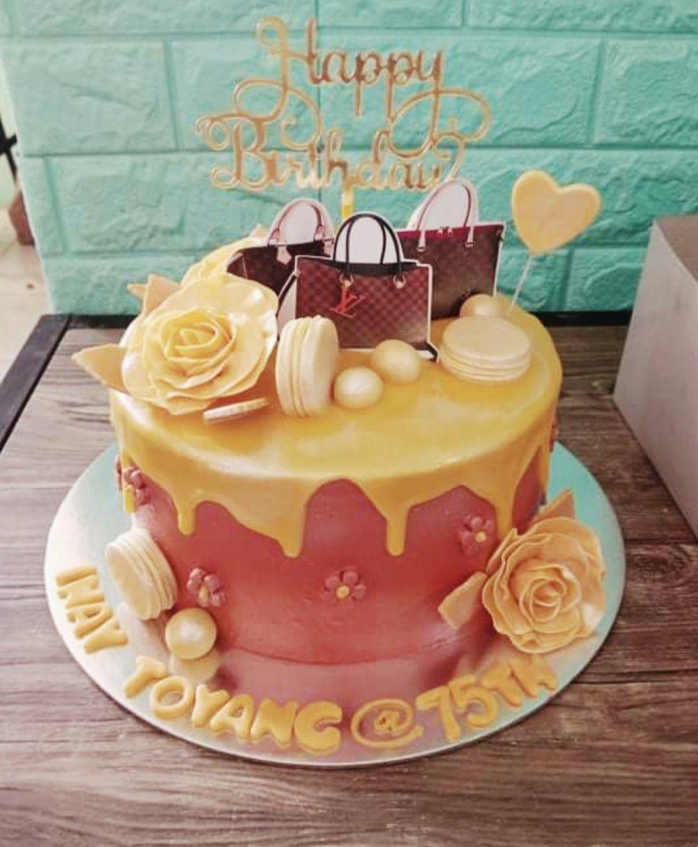 Red and gold luxury themed cake with Louis Vuitton bag printouts, gold roses, and a Happy Birthday topper.