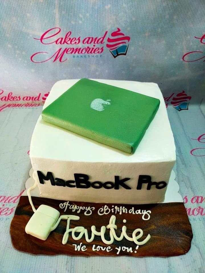 White square cake designed as a MacBook Pro with a green fondant laptop topper and a computer mouse on a brown fondant board.