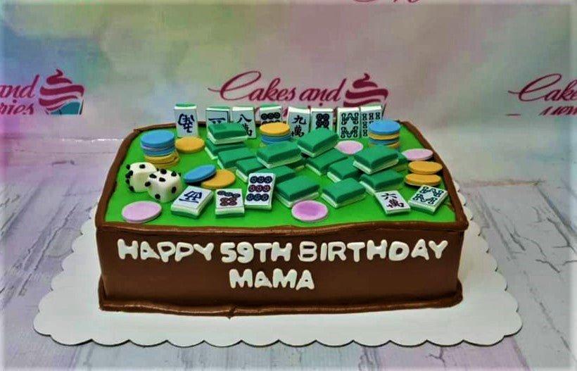 Mahjong themed rectangle cake with green icing top, brown sides, and edible mahjong tiles, chips, and dice decorations.