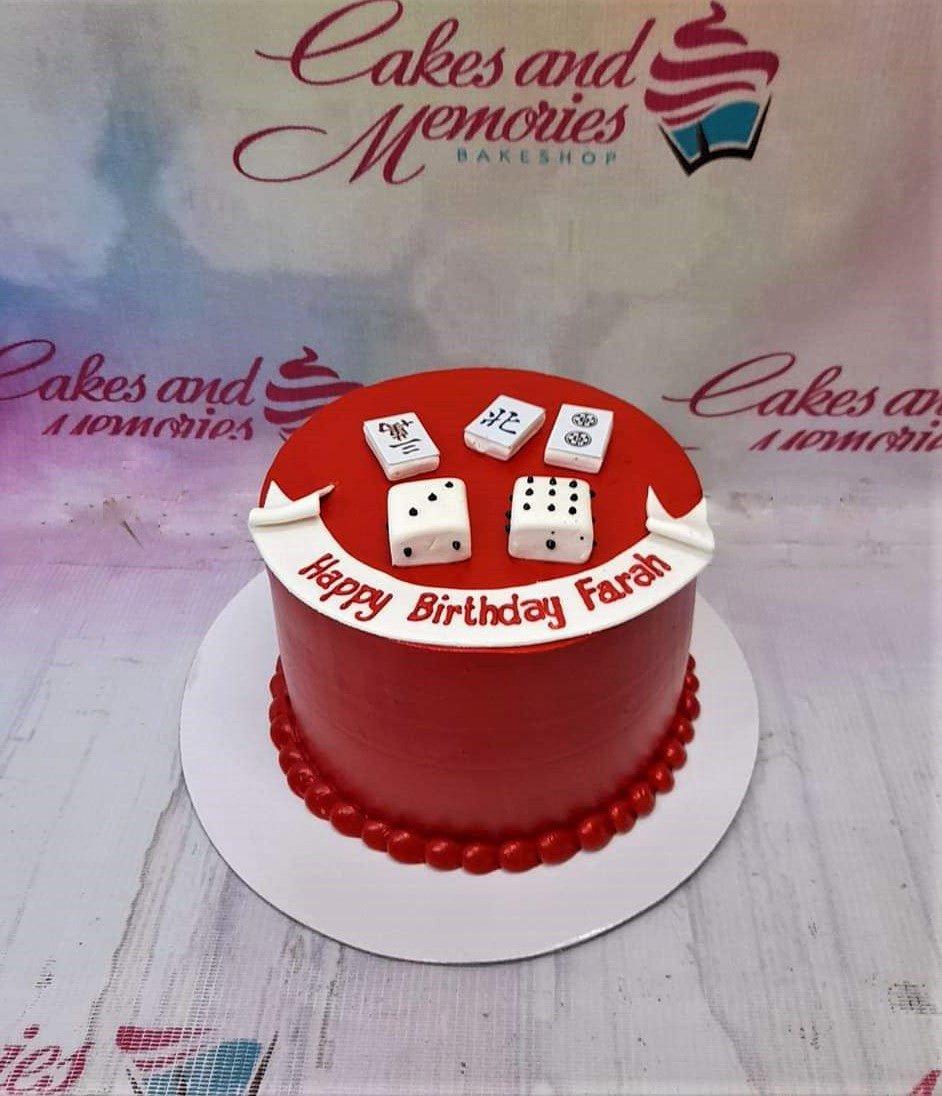 Red minimalist birthday cake with white mahjong tiles and dice toppers on a white banner message.