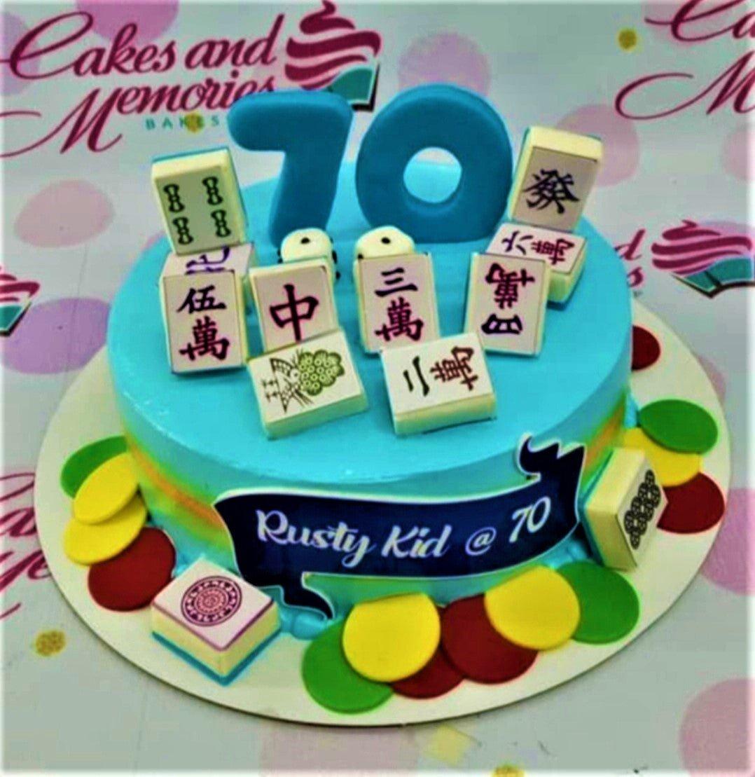 Light blue 70th birthday cake with mahjong tile toppers and colorful fondant circles around the base.