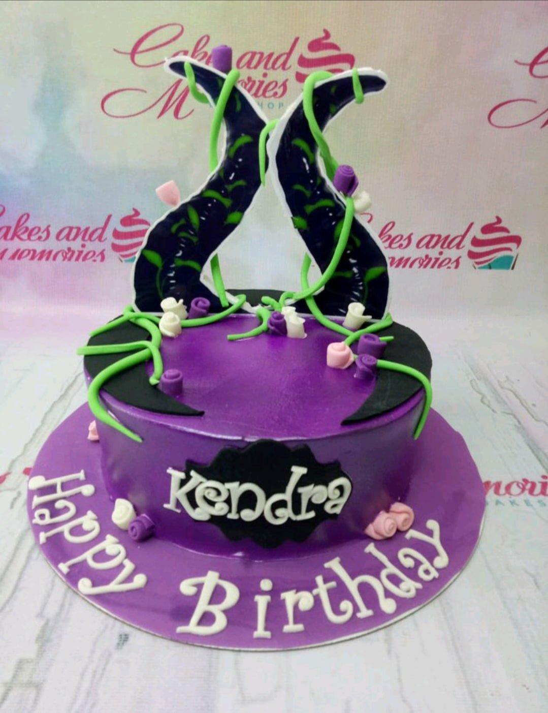 Purple Maleficent themed birthday cake with black horns, green vines, and pink and white icing roses.