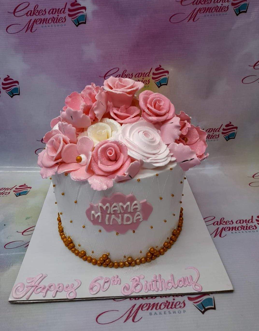 White single tier birthday cake for Mama Minda with a large cluster of pink and white gumpaste roses and gold dragees.