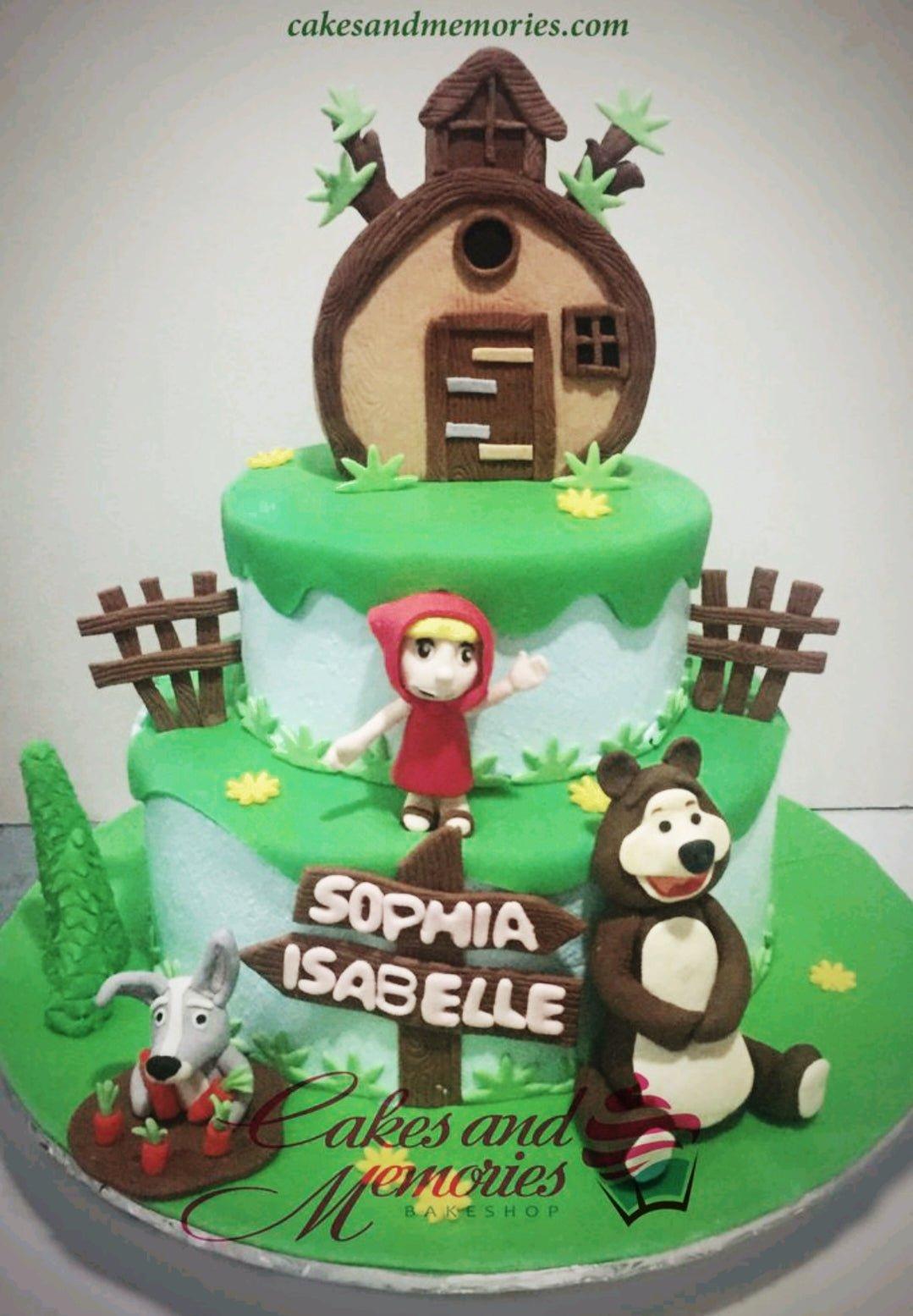 Masha and the Bear themed 2-tier fondant cake with a 3D edible house topper, Masha, Bear, and Rabbit figures on a green forest landscape.