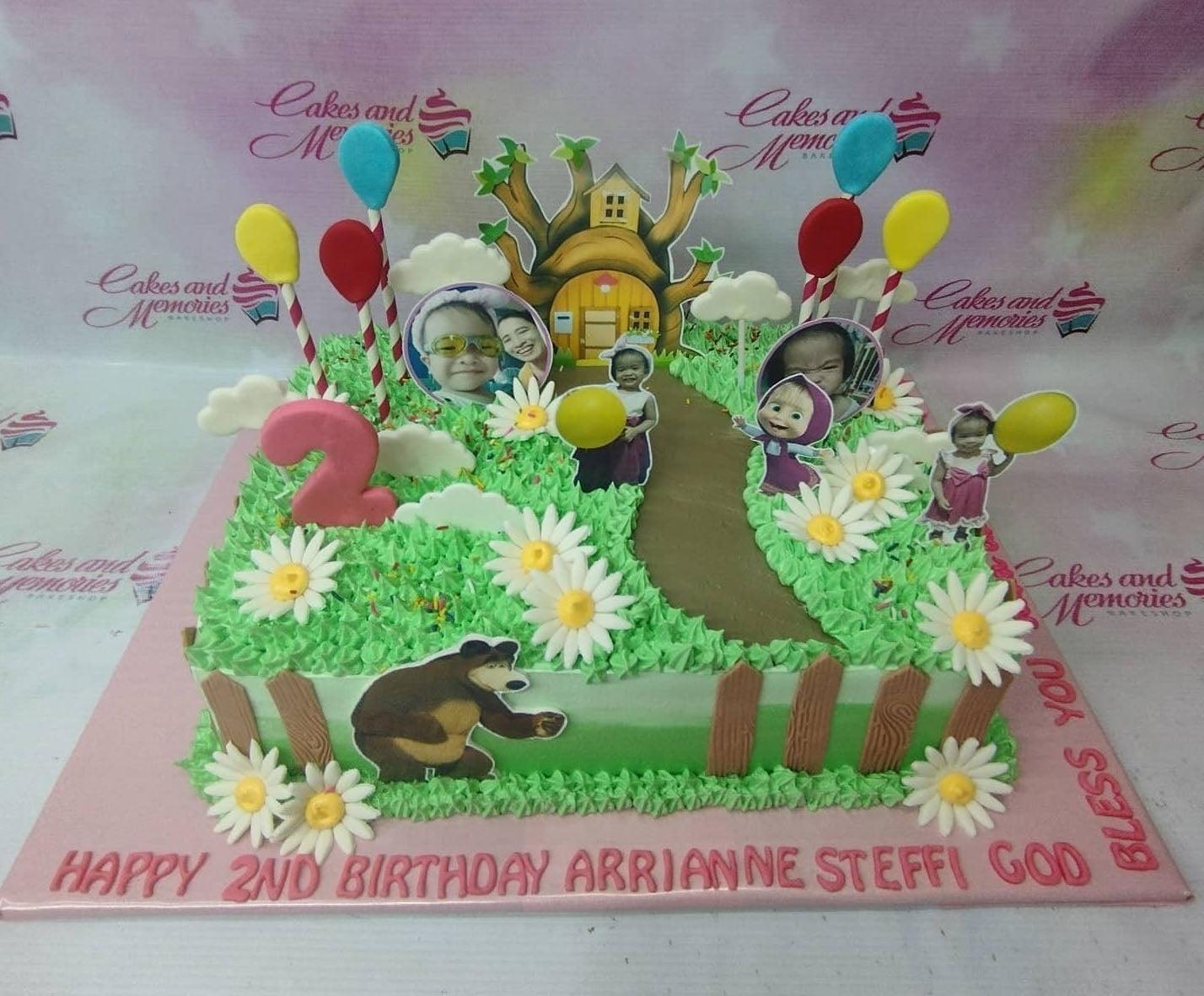 Masha and the Bear themed rectangle cake with green icing grass, daisy flowers, and character printouts for a 2nd birthday.
