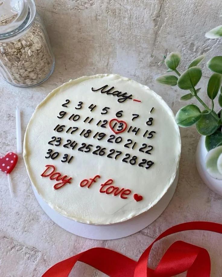 White bento cake with a black and red calendar design for May 13th and the message Day of Love.