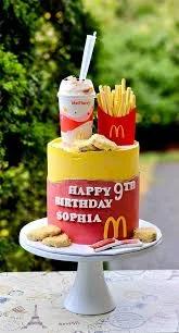 McDonald's themed birthday cake with yellow and red icing, topped with a milkshake cup, french fries, and chicken nuggets.