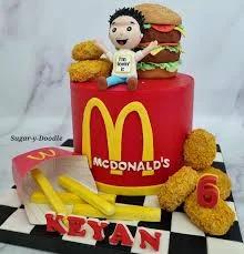 Red McDonald's themed birthday cake with fondant burger, nuggets, fries, and a custom boy figurine.