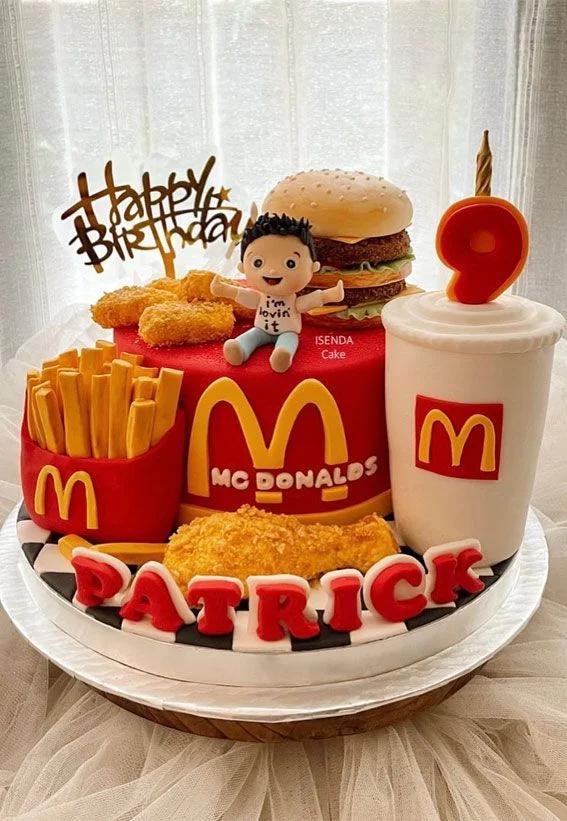 McDonald's themed red fondant cake with 3D edible burger, fries, nuggets, fried chicken, and a custom boy figurine.