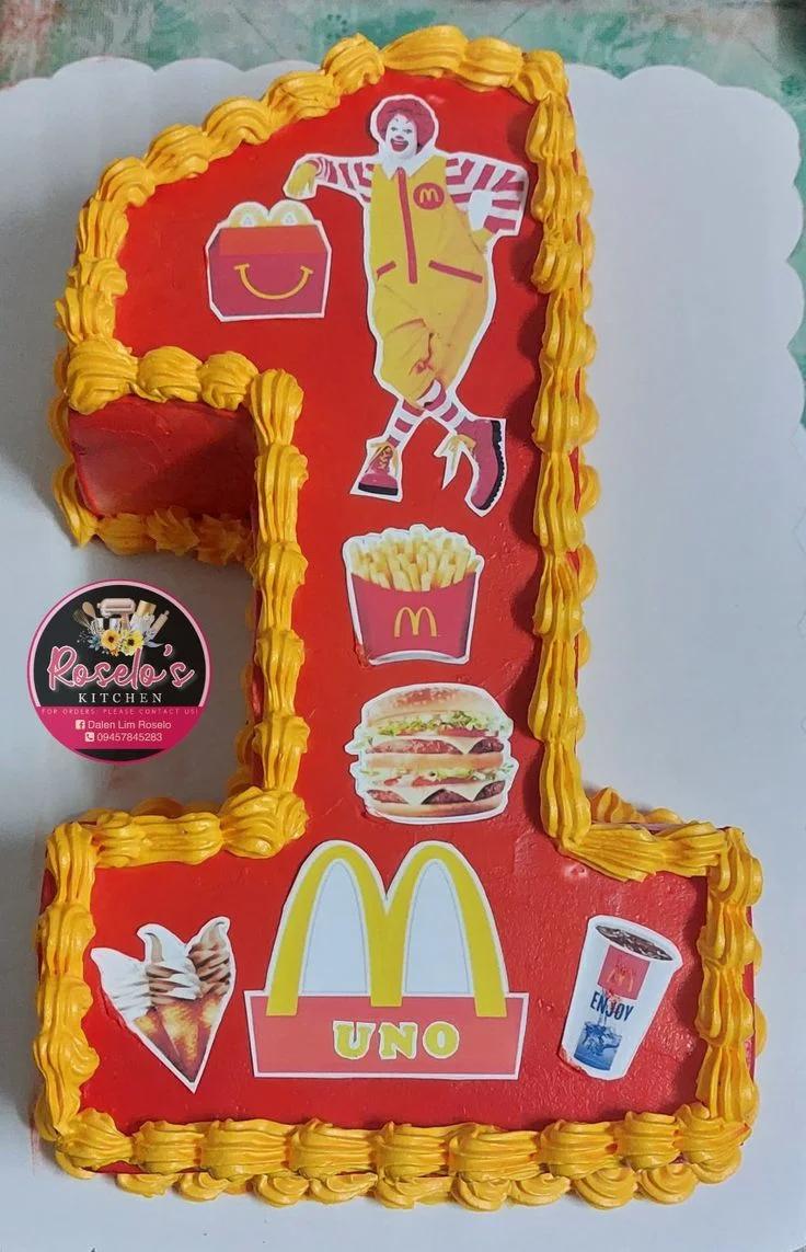 Number one shaped red cake with McDonald's themed printouts and yellow icing borders.