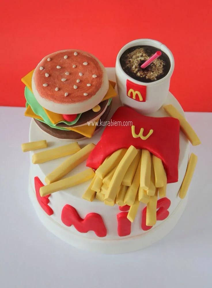 McDonald's themed fondant cake featuring a 3D burger, french fries, and a soda cup topper with red fondant name letters.