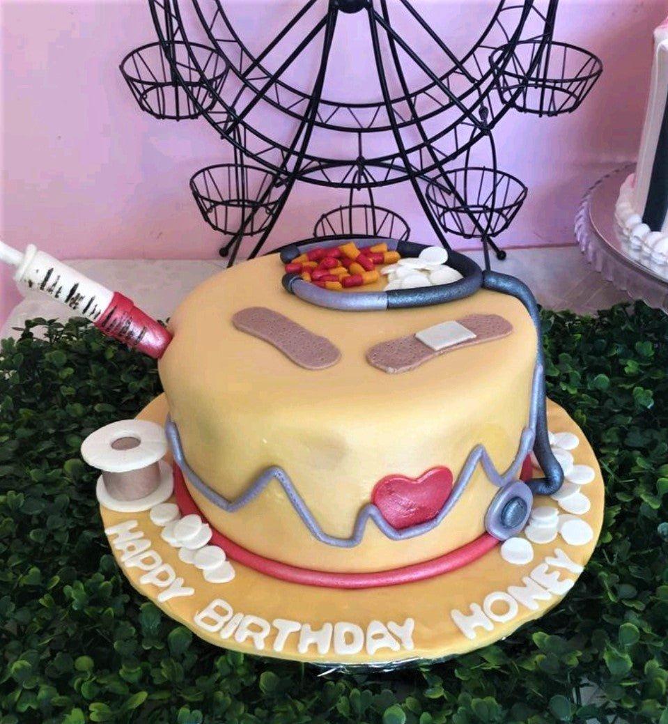 Medical themed birthday cake with fondant stethoscope, syringe, bandages, and pills on a tan base.