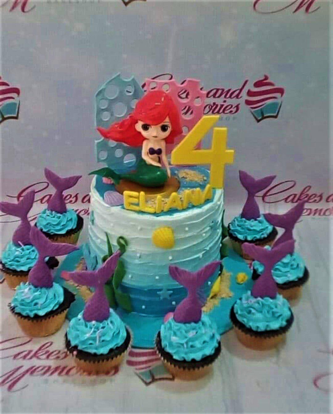 Mermaid themed birthday cake with Ariel figure, purple mermaid tails, and blue icing waves.