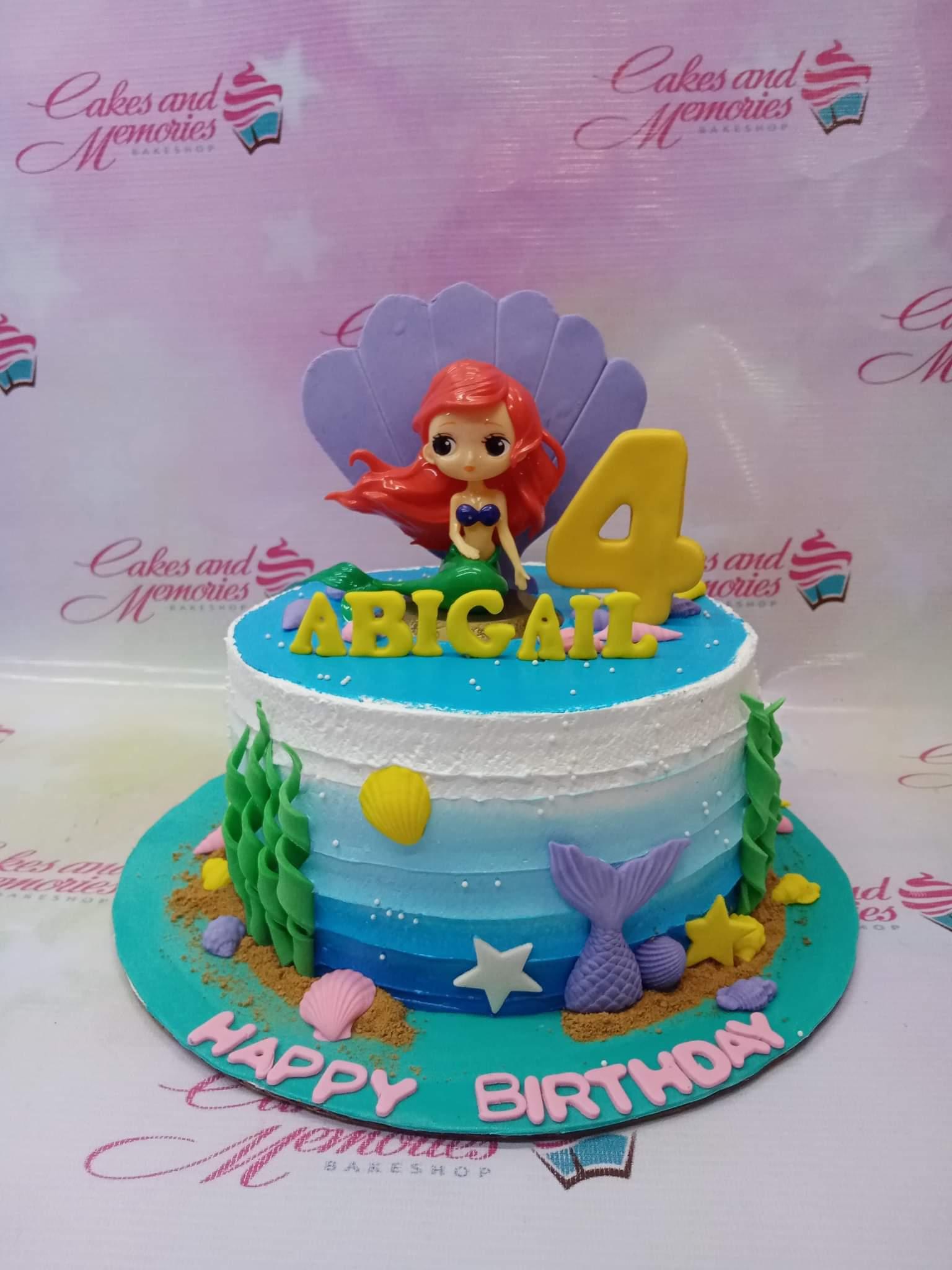 Blue ombre mermaid birthday cake with Ariel figurine, purple shell, and yellow number 4 topper