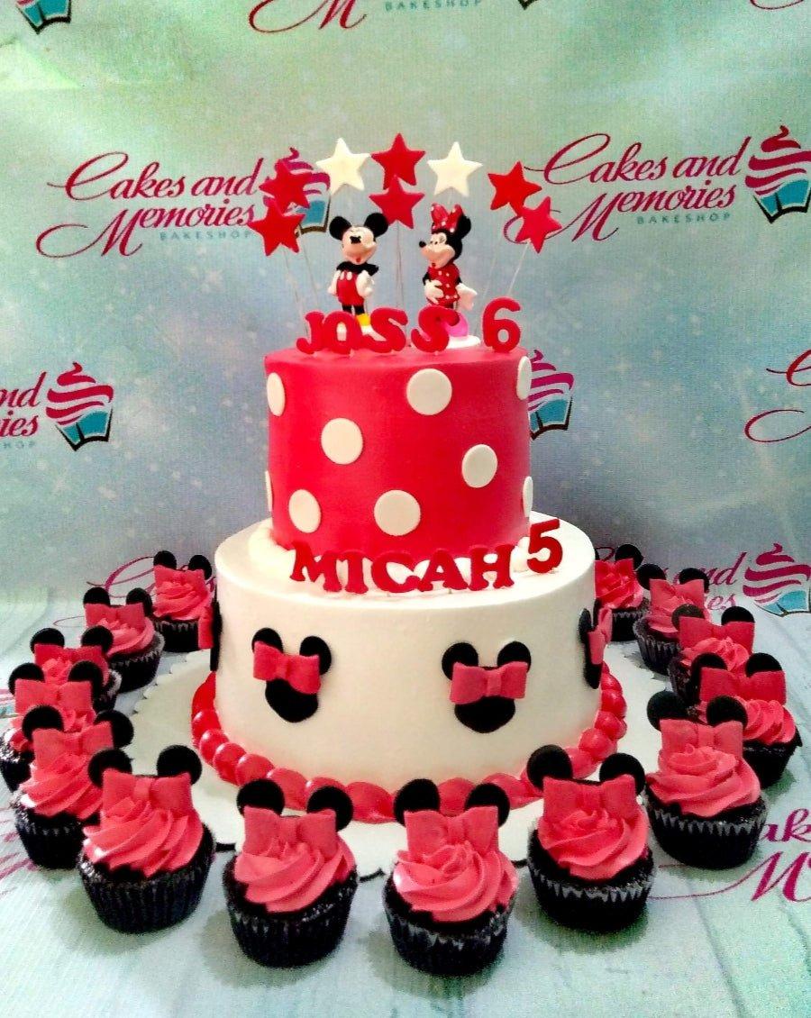 Two-tier Mickey and Minnie Mouse themed cake with red and white polka dots, black mouse silhouettes, and red icing rosettes.