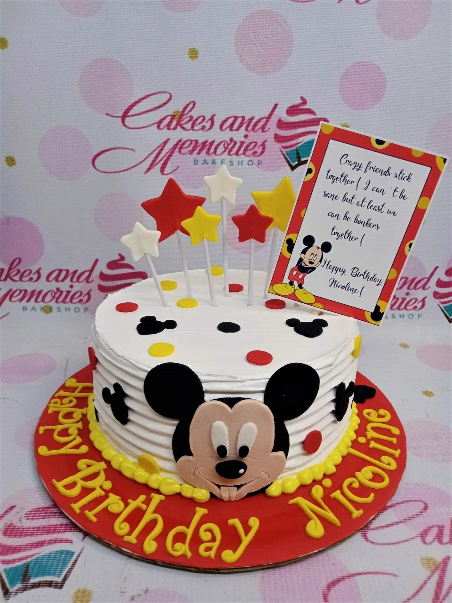 Mickey Mouse themed birthday cake with red, yellow, and black polka dots, star toppers, and a personalized message card.