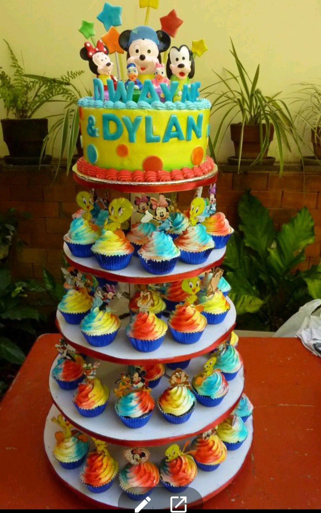 Yellow Mickey Mouse and friends themed birthday cake with colorful polka dots and a tiered cupcake stand.