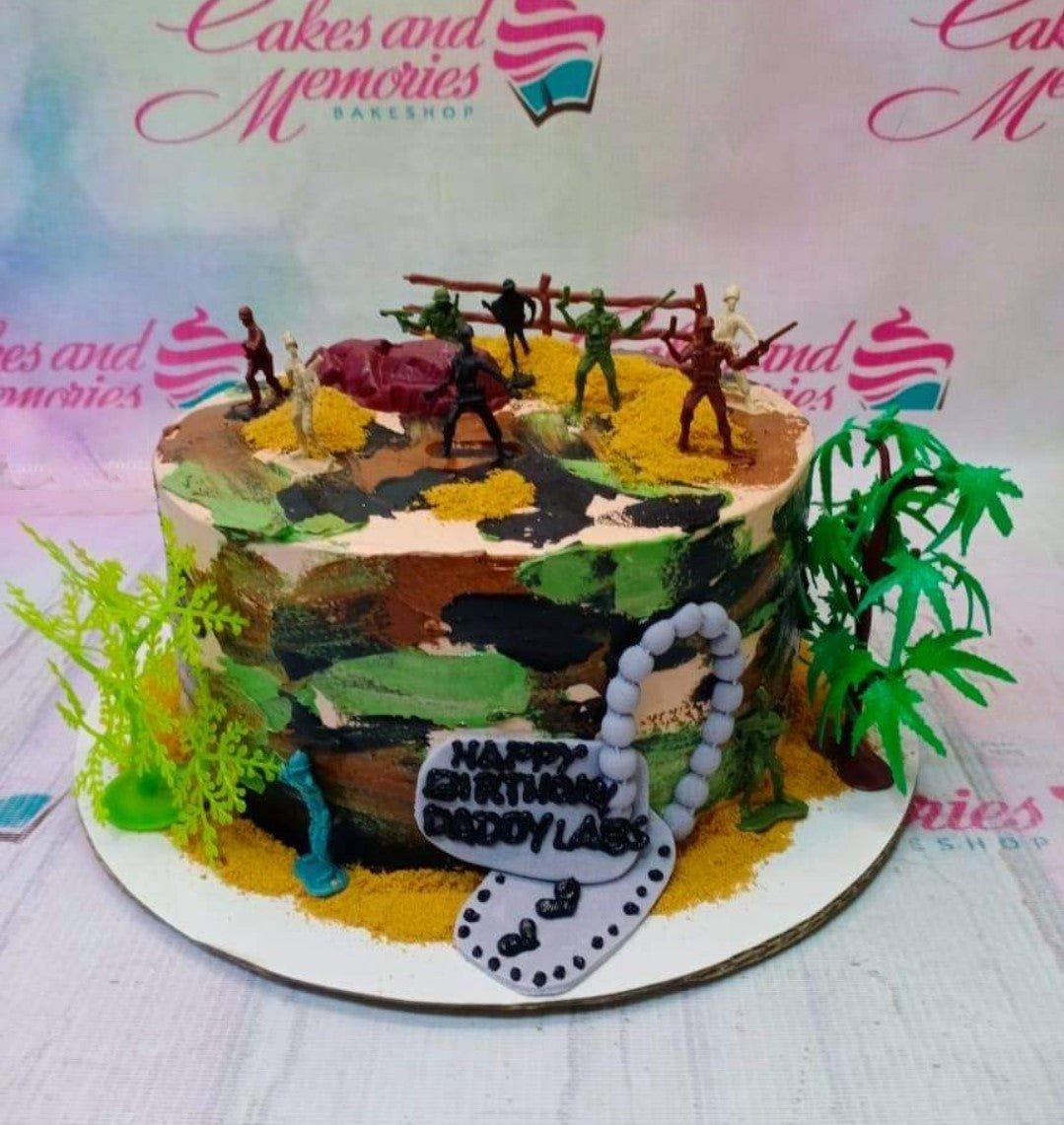 Camouflage military themed birthday cake with toy soldiers, plastic trees, and a dog tag message for Dadoy Labs.