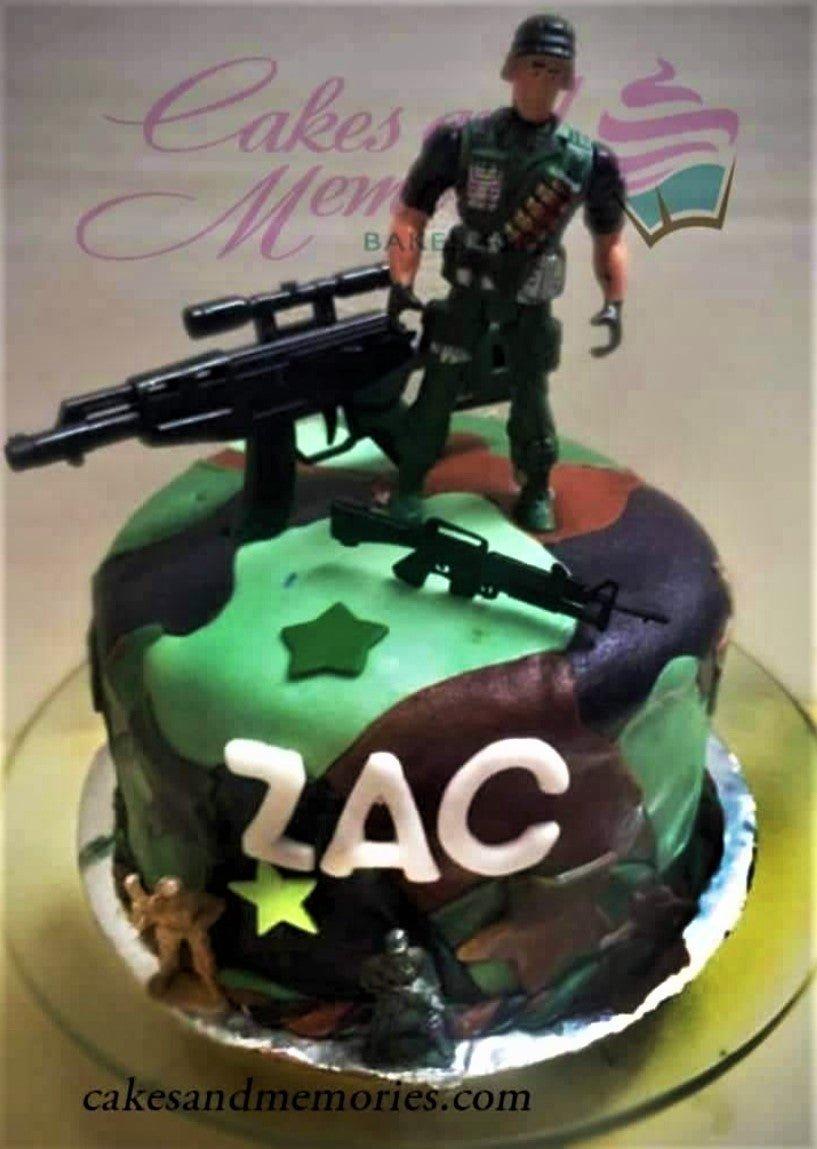 Camouflage military themed cake with soldier action figure and toy guns for Zac's birthday.
