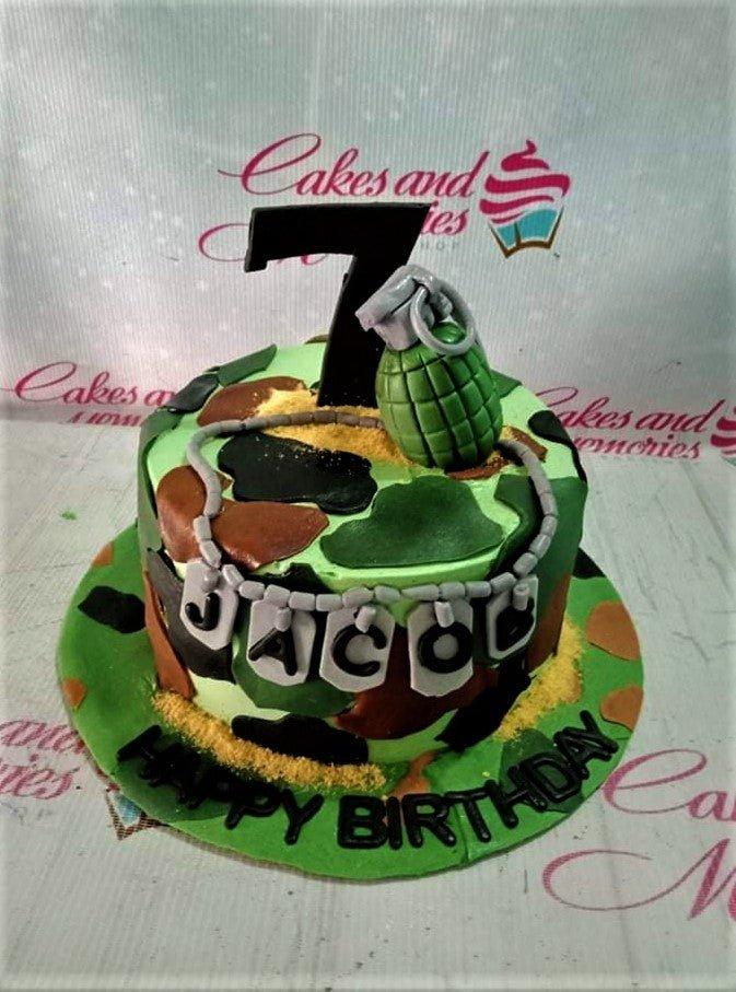 Camouflage military themed birthday cake with a green grenade topper, black number 7, and dog tag name banner for Jacob.