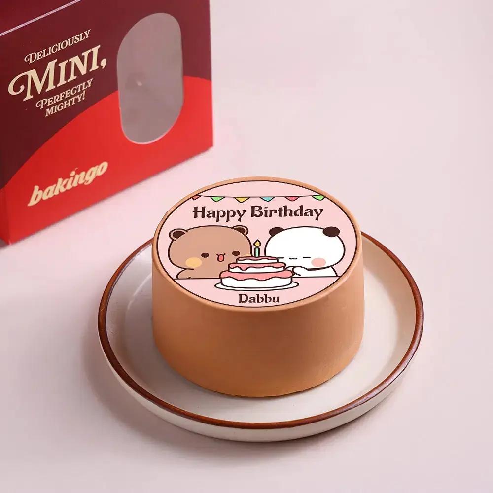Bento cake with a pink top featuring a printed illustration of two cute bears celebrating with a cake and a Happy Birthday message.